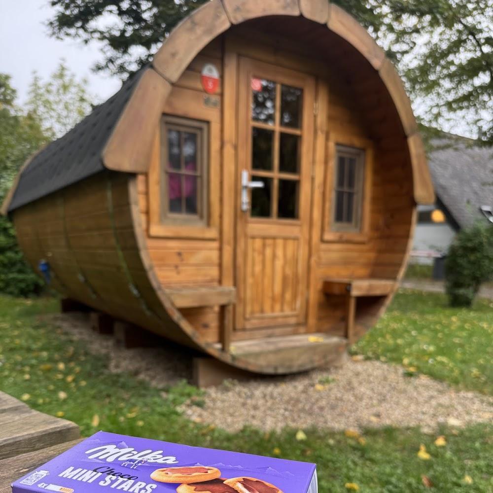 A wooden barrel-shaped cabin with a door and windows.